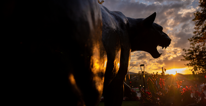 The Pitt Panther statue in the foreground of a Pittsburgh sunrise.